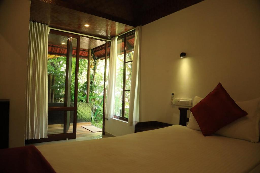 a bedroom with a bed and a large window at Lakefront Beach Homes in Cherai Beach