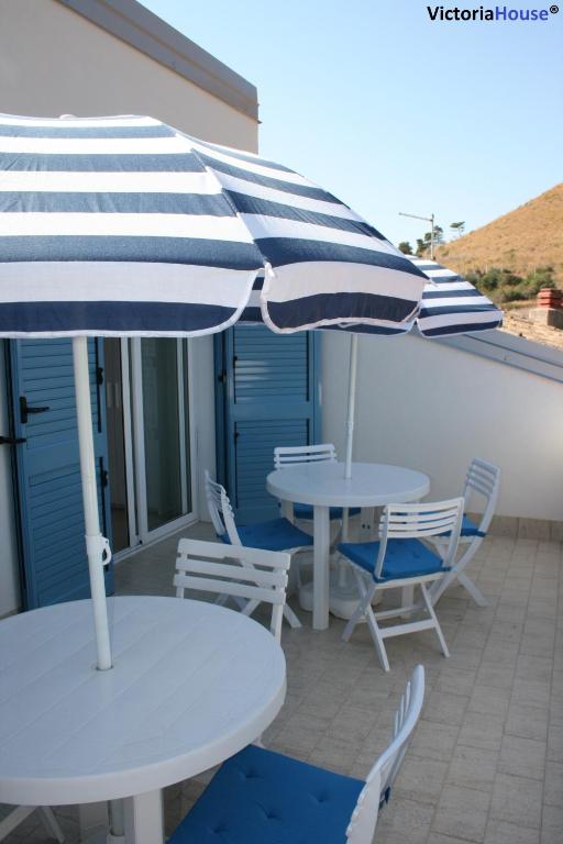 two tables and chairs with umbrellas on a patio at Victoria House Scopello in Scopello