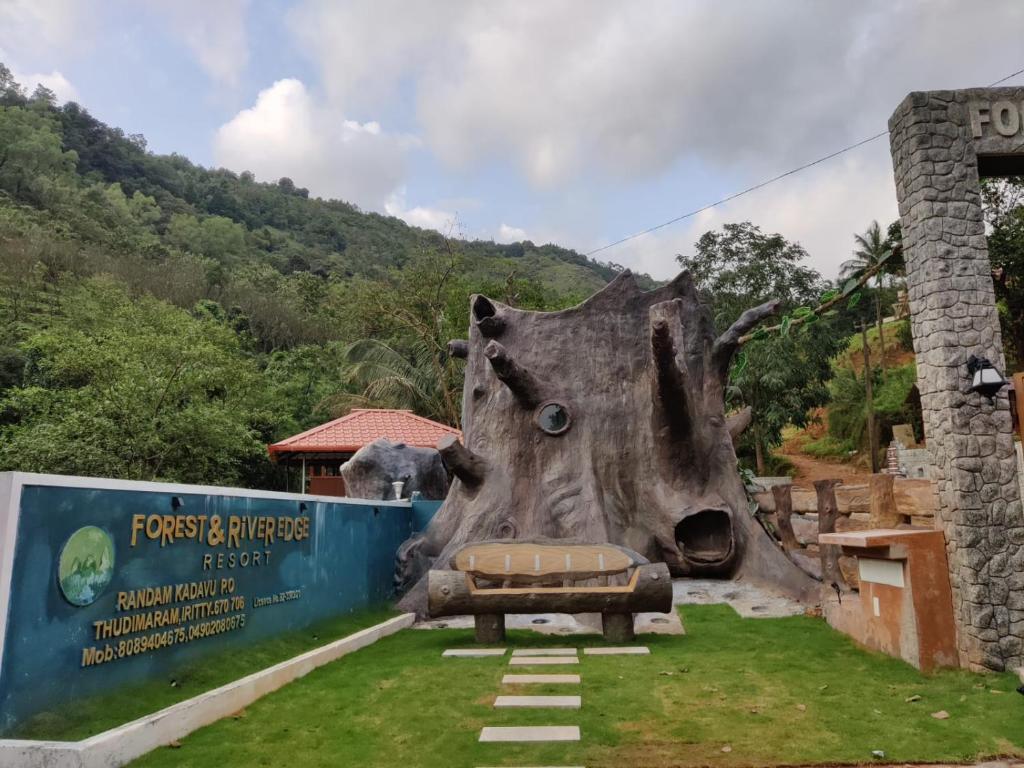 una statua di un tronco d'albero con un letto nell'erba di Forest and River Edge Resort a Kannur