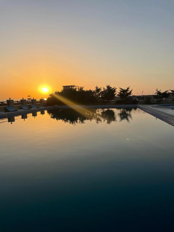 um pôr-do-sol sobre uma piscina de água com o pôr-do-sol em Style Home Buzovna em Baku