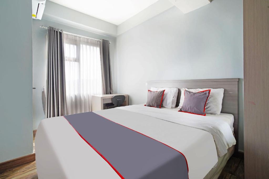 ein Schlafzimmer mit einem großen weißen Bett mit roten Kissen in der Unterkunft Collection O 91566 Edurent Bandung in Sayang