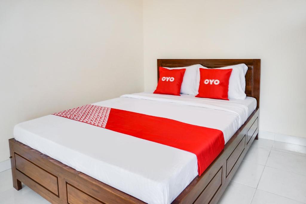 1 dormitorio con 1 cama con almohadas rojas en OYO Life 91569 Omah Wijaya Kusuma Syariah, en Malang