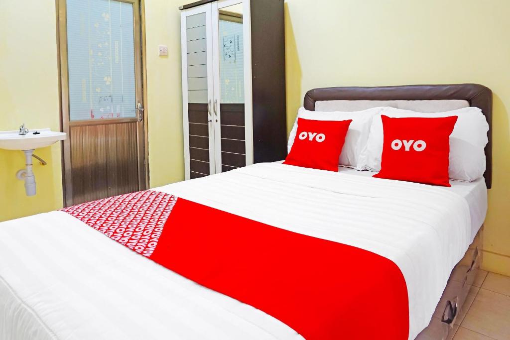 a bedroom with a large bed with red pillows at Super OYO 91568 Trisna Srabah Resort Homestay & Resto in Kalangbret