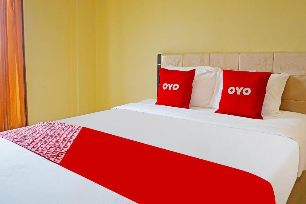 einem roten und weißen Bett mit zwei roten Kissen darauf in der Unterkunft OYO 91580 Kost Bougenville Syariah in Madiun