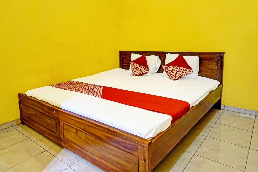 a wooden bed with red and white pillows on it at OYO 91573 Hotel Family Blitar in Blitar