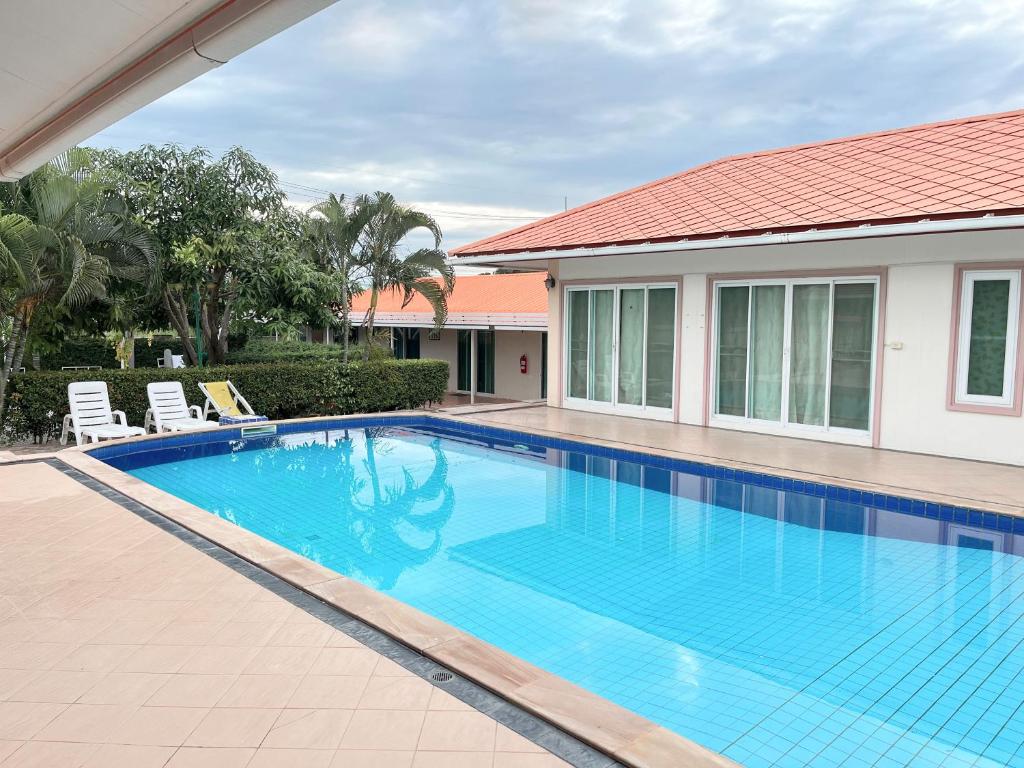 a swimming pool with chairs and a house at Home JANO in Cha Am