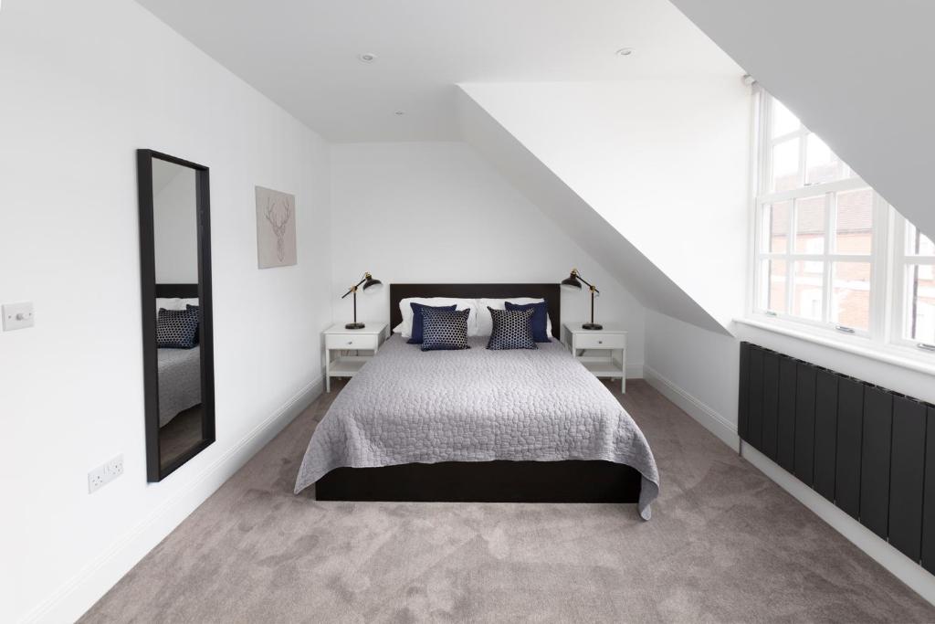 a white bedroom with a bed and two windows at Hampden Apartments - The William in Eton