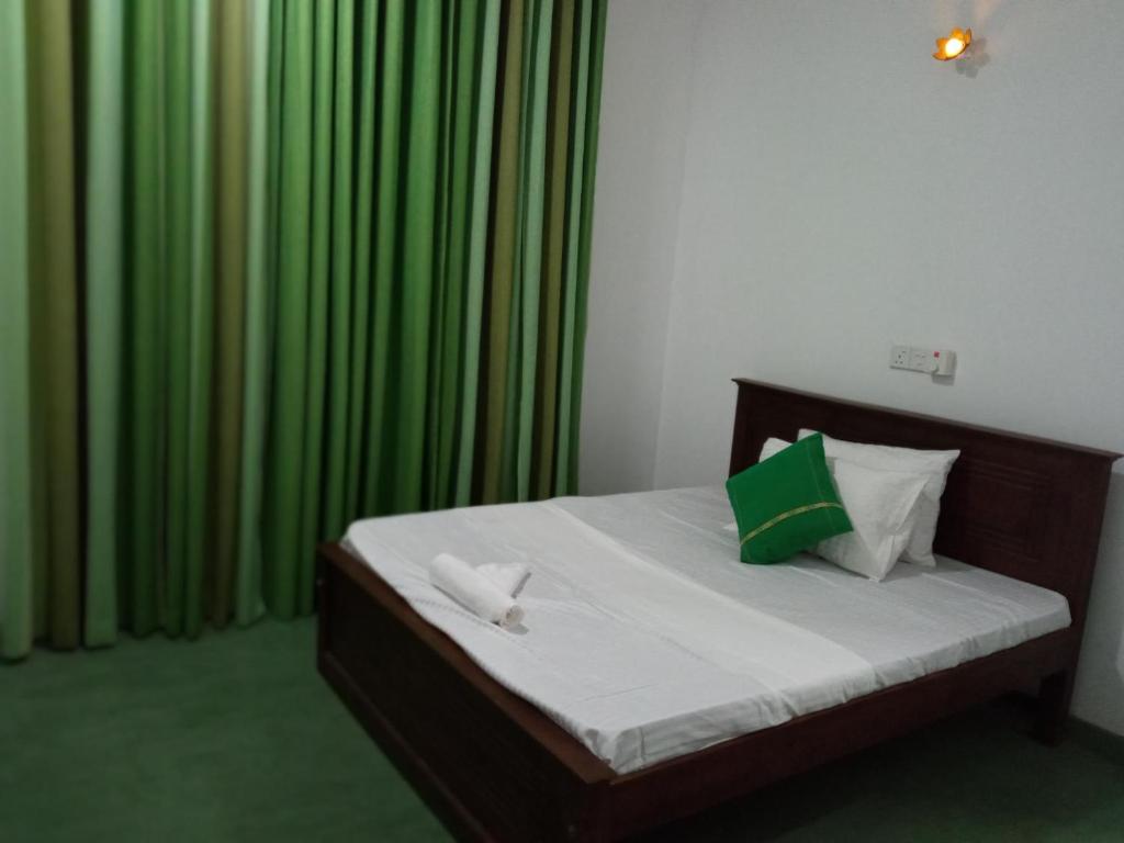 a bedroom with a bed with green curtains at Ridmi Home Stay in Karagampitiya