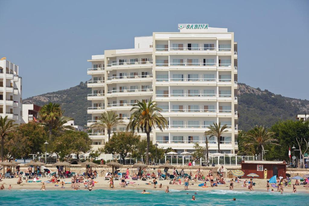 un grupo de personas en una playa frente a un hotel en Hotel Sabina, en Cala Millor