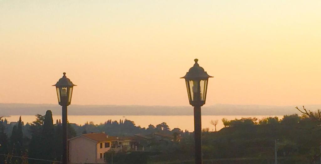 zwei Laternen mit Sonnenuntergang im Hintergrund in der Unterkunft Gardasee -RESIDENZA POETICA-Garda lake in Cavaion Veronese