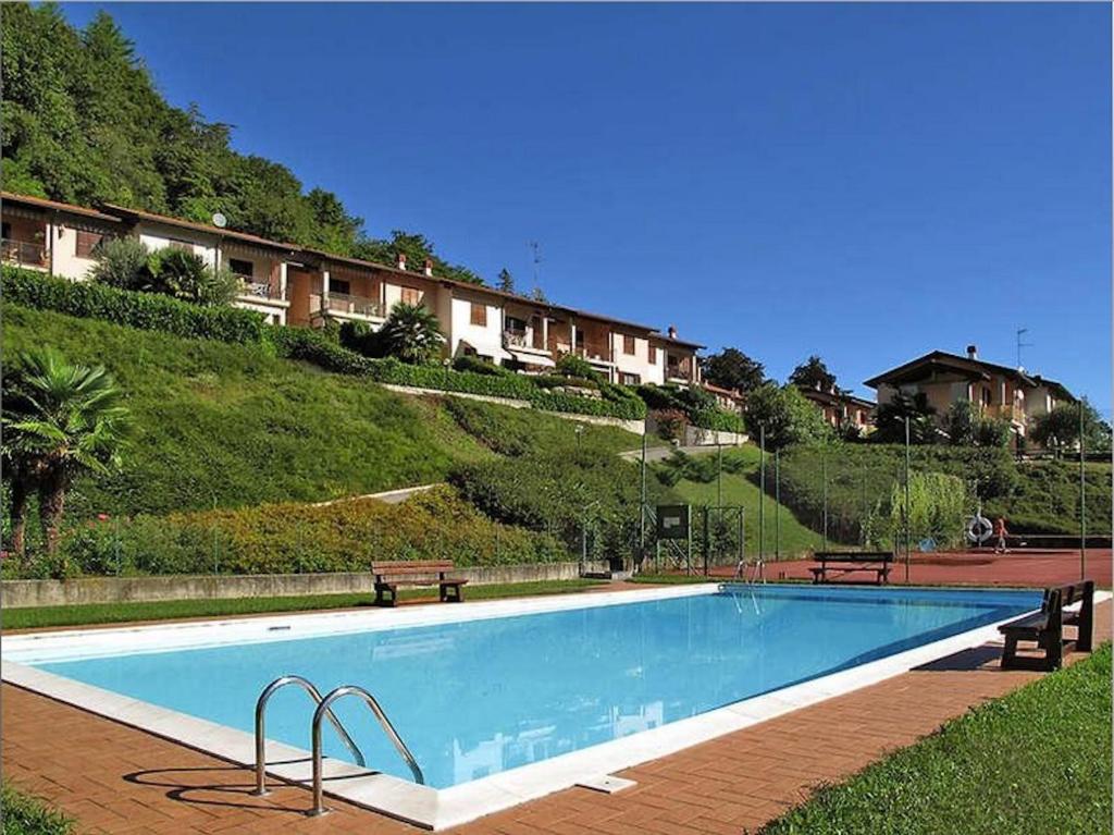 una gran piscina con 2 bancos junto a una colina en Residenza La Rocca, en Castello Valsolda
