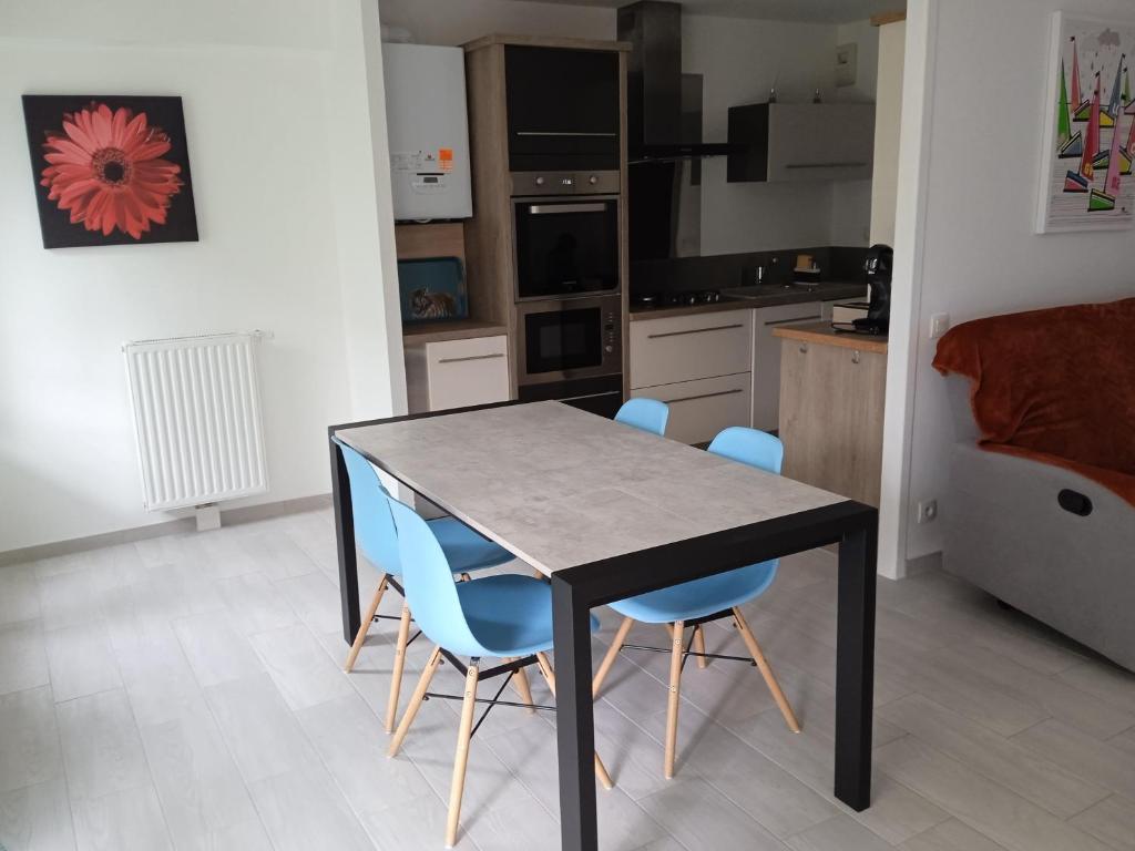 a kitchen with a table and blue chairs at Korelo in Ploemeur