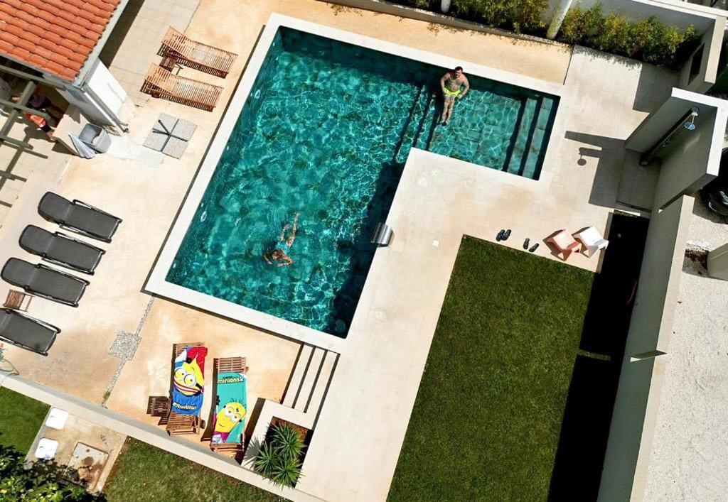 an overhead view of a swimming pool with people in it at Linc Rooms & Apartments in Banjole