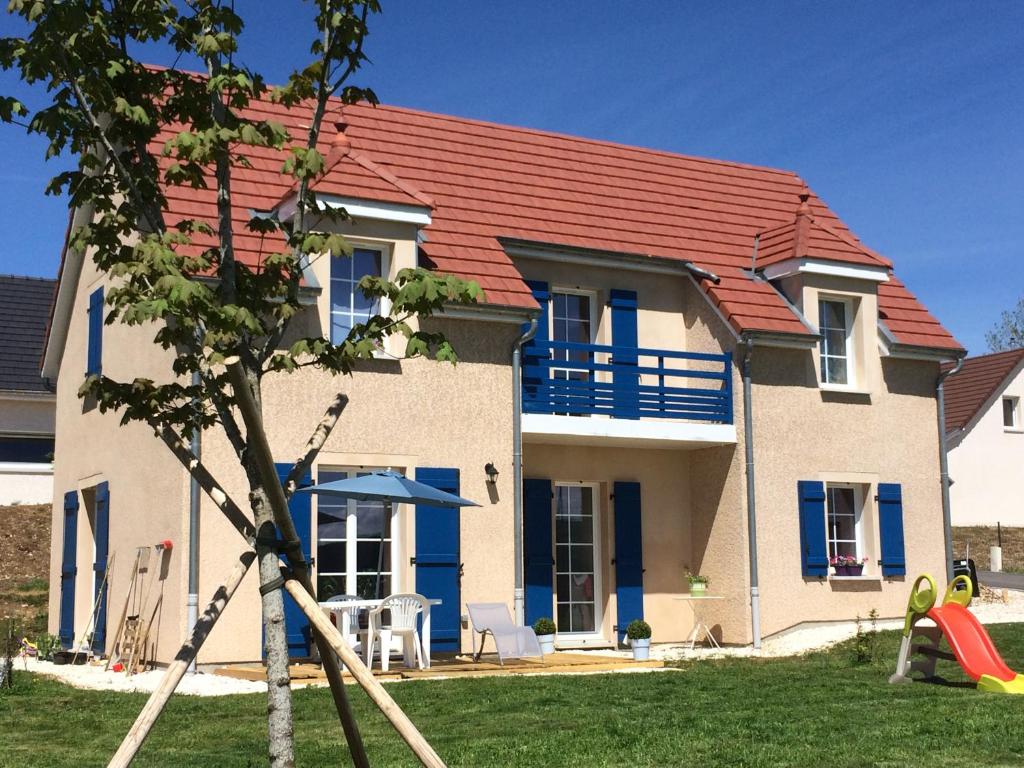 ein Haus mit einem roten Dach und einem Spielplatz in der Unterkunft Gîte en pleine nature au coeur du silence in Laviron