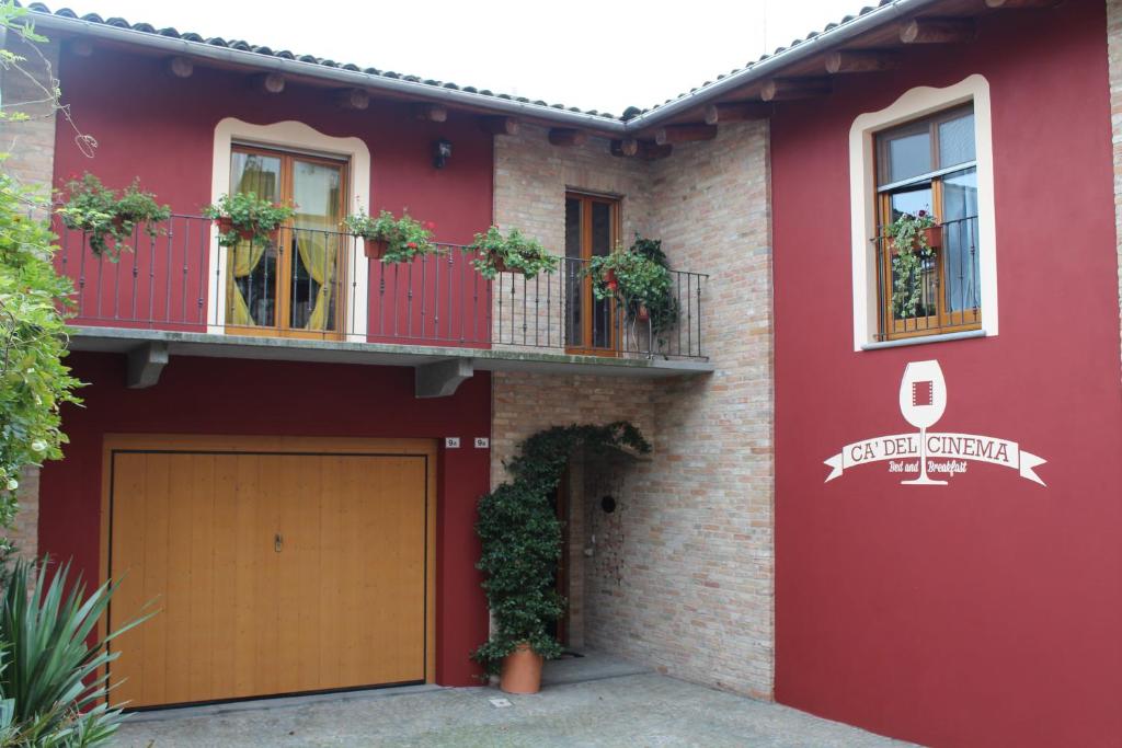 a red house with a garage and a balcony at Holiday home Ca' del Cinema in Mombercelli