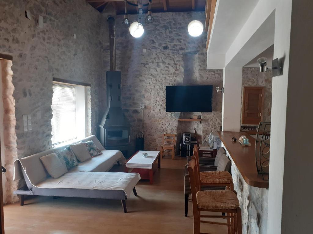 a living room with a couch and a tv at Tsitalia cottage house in Leonidion