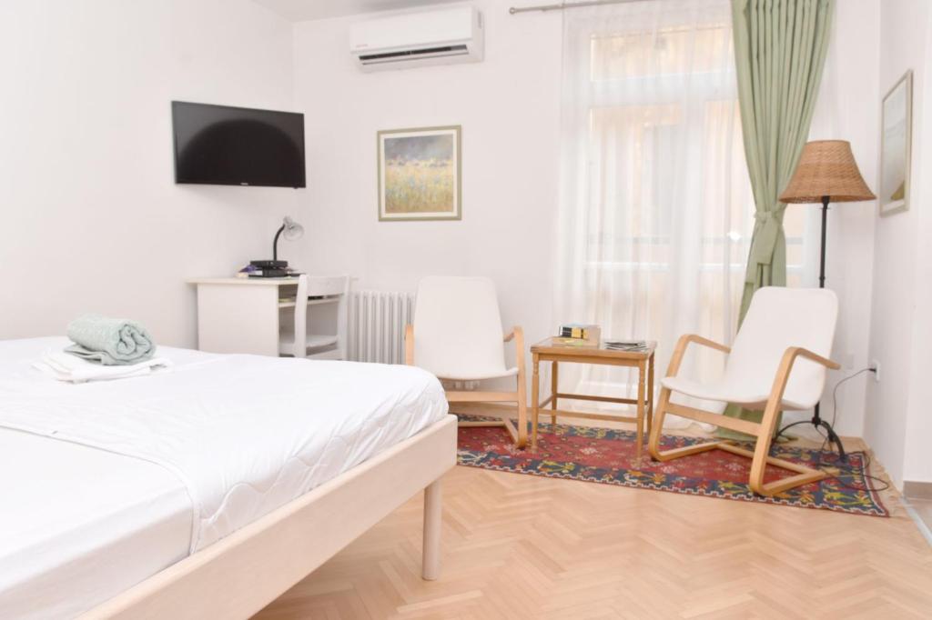 Un dormitorio con una cama, una silla y una ventana en Charming Studio in City Center-Excellent Location, en Sarajevo