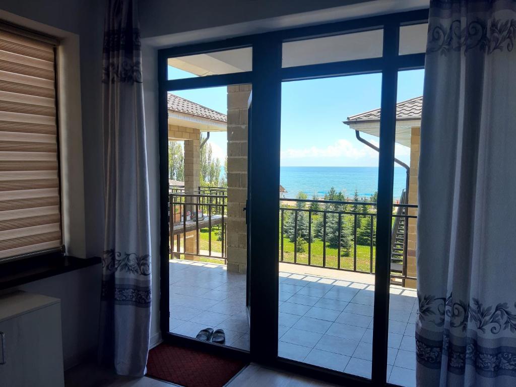 una puerta a un balcón con vistas al océano en Guest house Simiram, en Cholpon-Ata