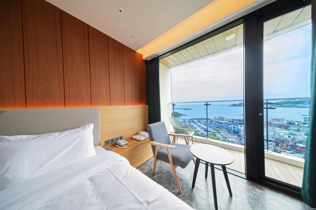 1 dormitorio con cama, mesa y ventana en The Club Hotel Gijang Yeonhwari en Busan