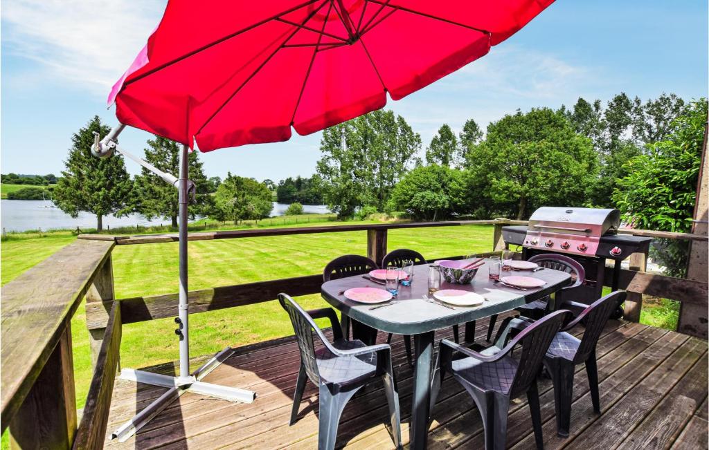 una mesa con sillas y una sombrilla roja en una terraza en Beautiful Home In Vire Normandie With Lake View 