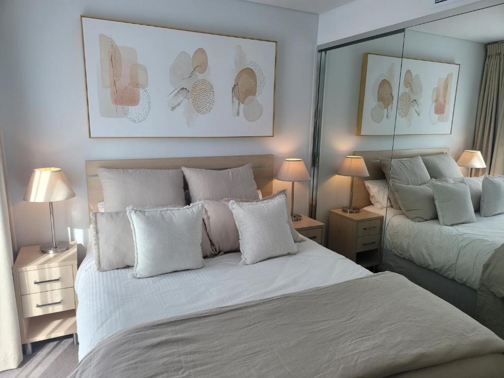 1 dormitorio con 2 camas y almohadas blancas en CBD Deluxe Private 2 Bedroom Apartment, en Adelaida