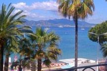 a view of a beach with palm trees and the ocean at Apartment on the Croisette with sea view in Cannes