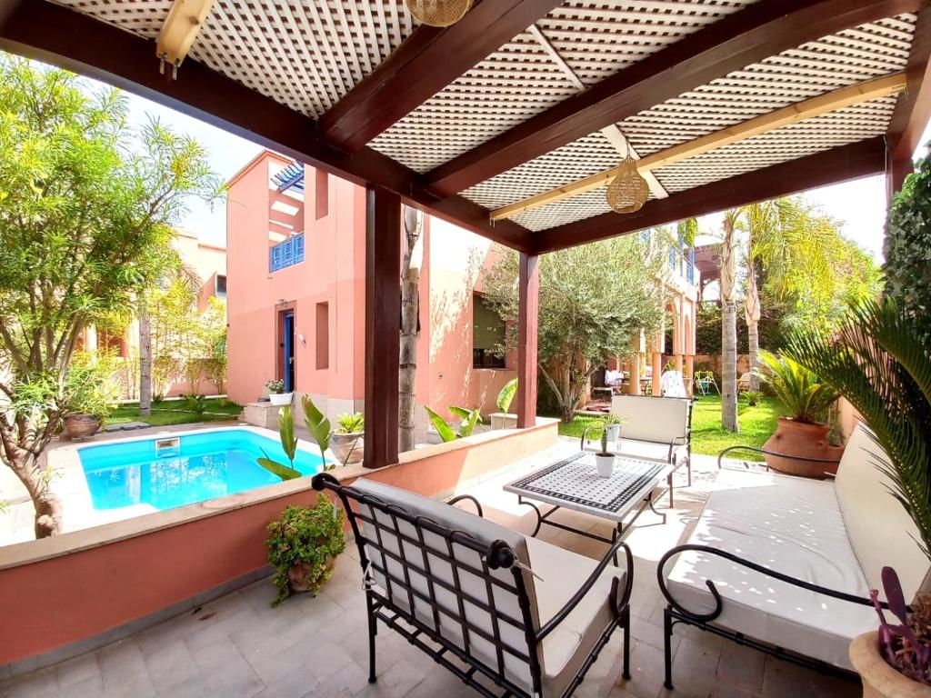 un patio al aire libre con piscina y pérgola en CYCAS VILLA TARGA GARDEN -Only Family, en Marrakech