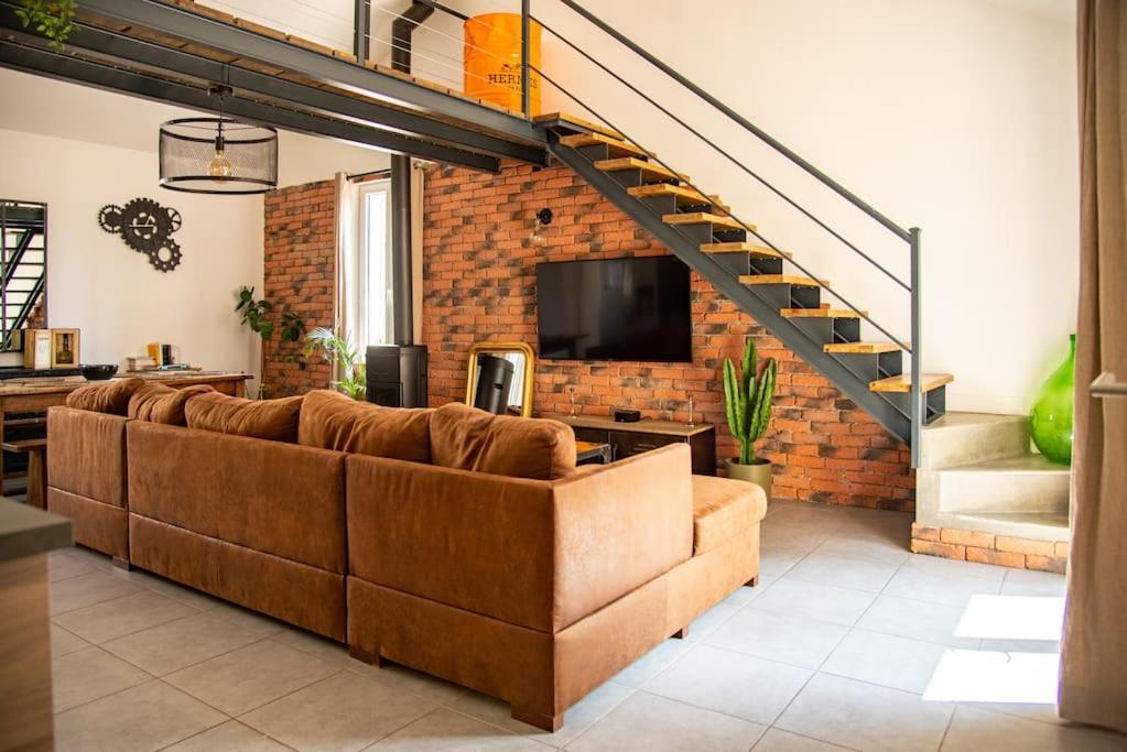ein Wohnzimmer mit einer Couch und einer Treppe in der Unterkunft Loft Évasion - Garage & Spa proche du centre historique in Avignon