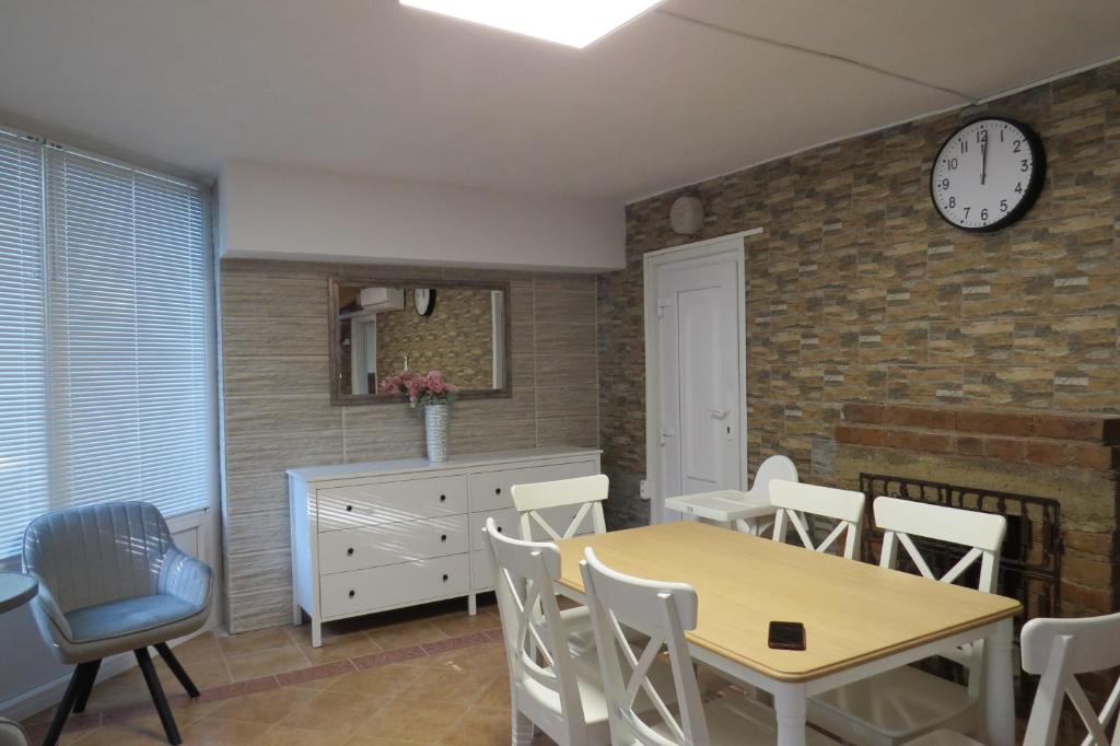 a dining room with a table and chairs and a clock at Szitakötő vendégház in Mártély