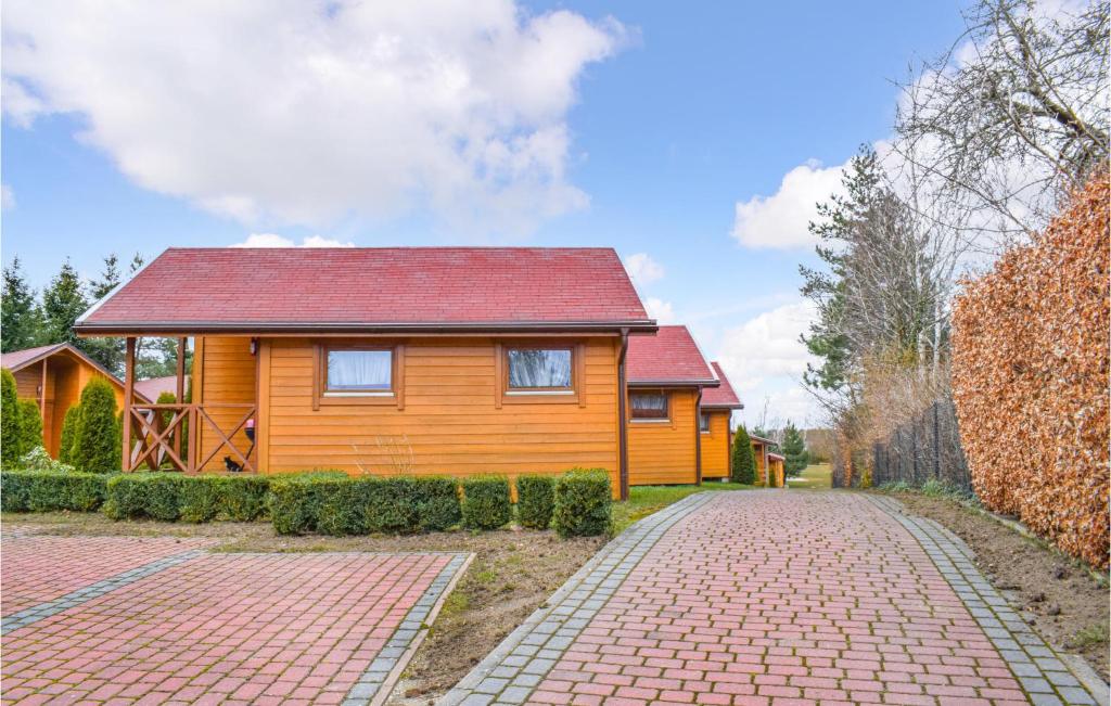 a wooden house with a red roof on a brick road at Nice Home In Jaroslawiec With 2 Bedrooms in Jarosławiec