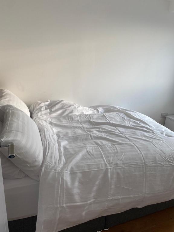 een ongemaakt bed met witte lakens erop bij Morden 1 bedroom City- Apt Central stylish living in Croydon