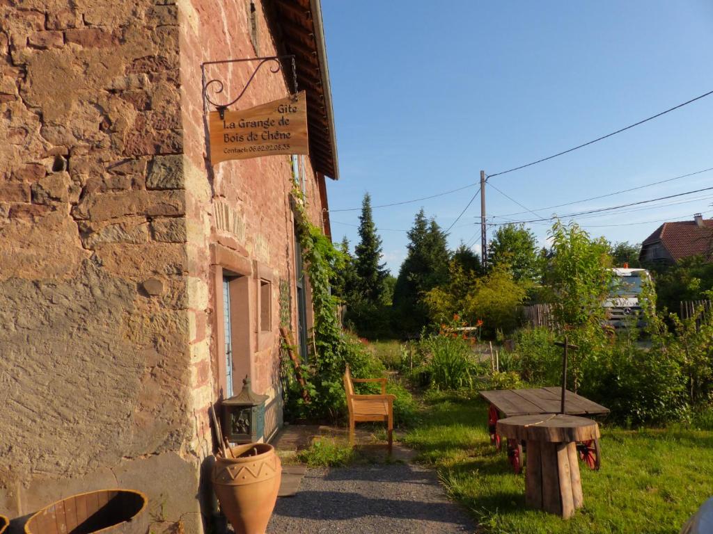 un edificio de piedra con un cartel en el costado en La Grange de Bois de Chêne, en Phalsbourg