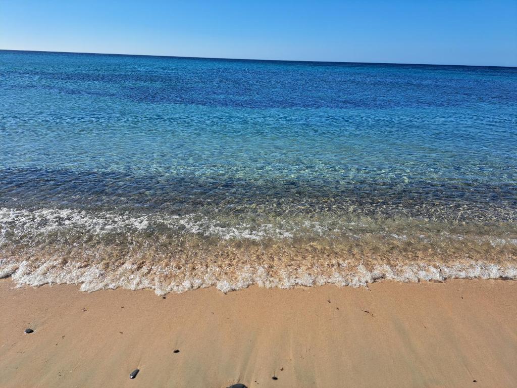 uma praia com o oceano e a areia e a água em Da Zio Mario em Flumini di Quartu