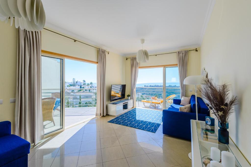 een woonkamer met een blauwe bank en een groot raam bij Ocean view Apartment with 3 spacious Terraces, 2 Swimming pools & Tennis court in Albufeira