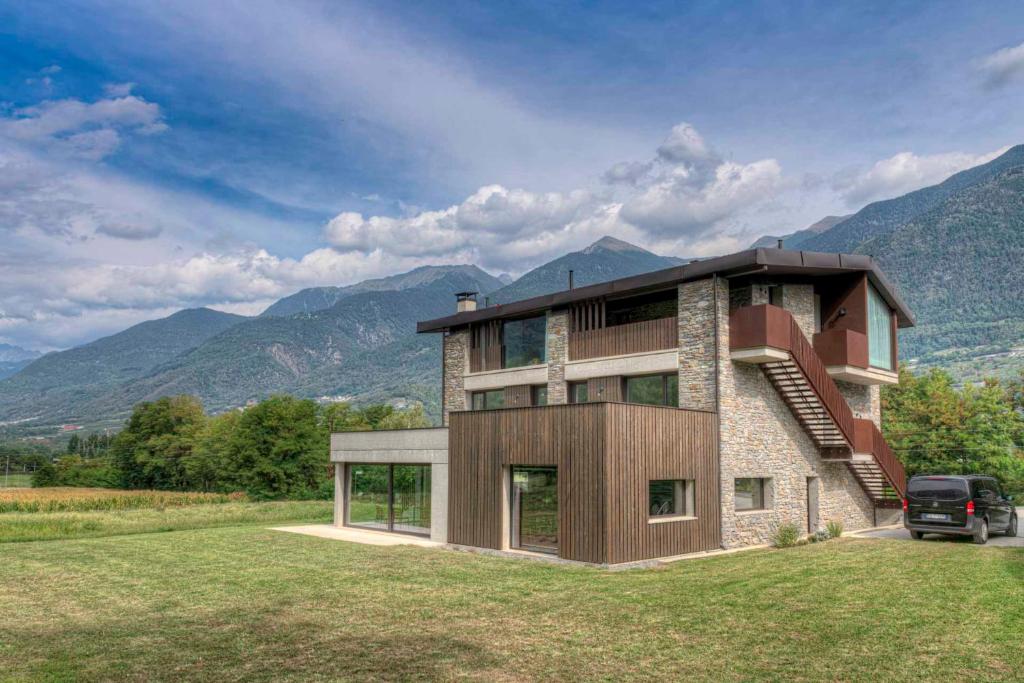 duży dom z górami w tle w obiekcie Agriturismo B&B Caffè e Vino w mieście Sondrio