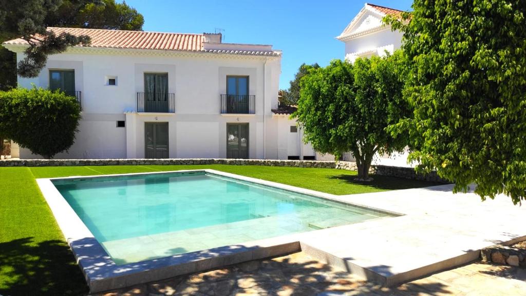 una villa con piscina di fronte a una casa di Hostal Residencia Alma a Port d'Alcudia