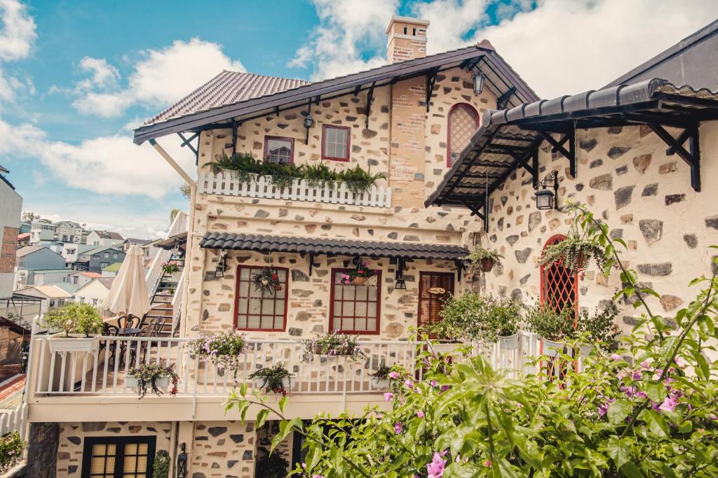 a stone house with a balcony and flowers at Villa Hoa Da in Da Lat