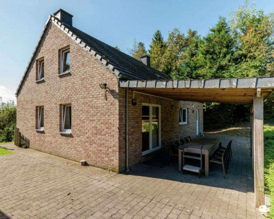 a brick house with a patio and a table at Villa Du bonheur met Sauna en Jacuzzi in Somme-Leuze