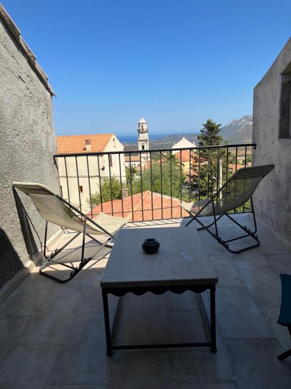 a patio with two chairs and a table on a balcony at Casa Calenzana in Calenzana