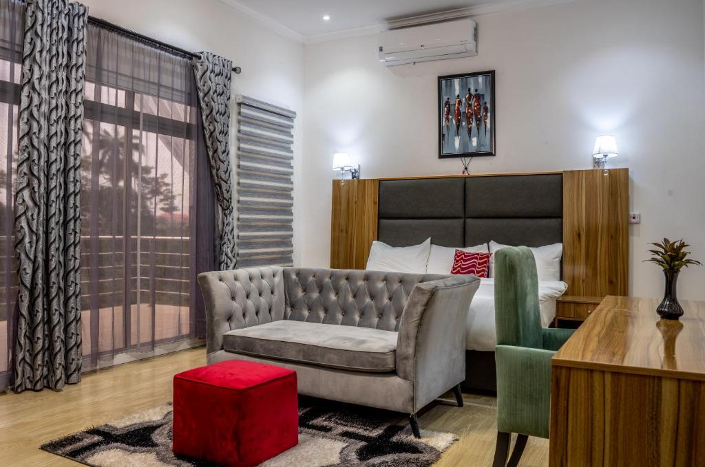 ein Schlafzimmer mit einem Bett, einem Sofa und einem Stuhl in der Unterkunft Nelson Mandela Gardens in Okpanam
