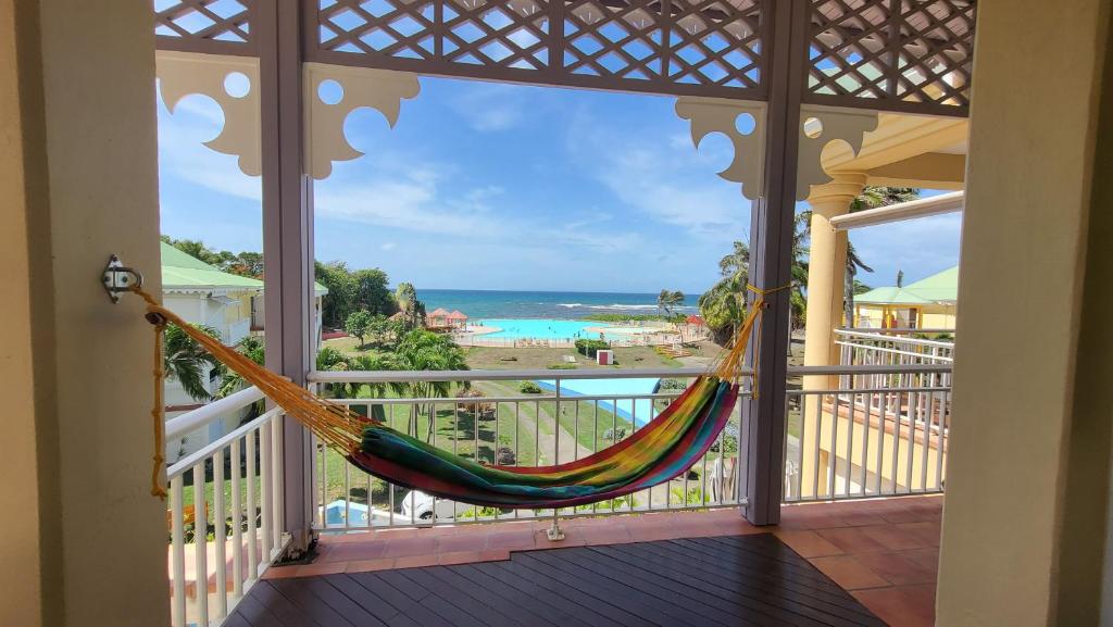 uma rede de descanso numa varanda com vista para o oceano em Kaz Loriké - Vue Mer & piscine exceptionnelle - Anse des Rochers em Saint-François