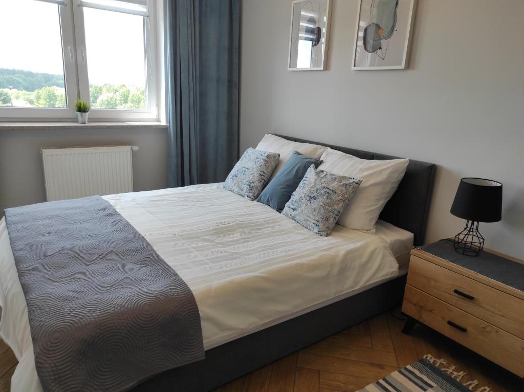 1 dormitorio con cama con almohadas y ventana en Apartament Tuwima Park en Ełk