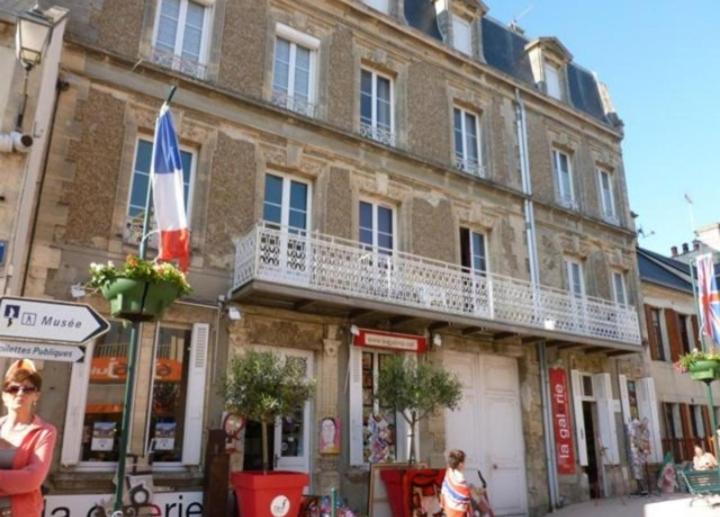 een groot bakstenen gebouw met een balkon in een straat bij Studio Neptune in Arromanches-les-Bains