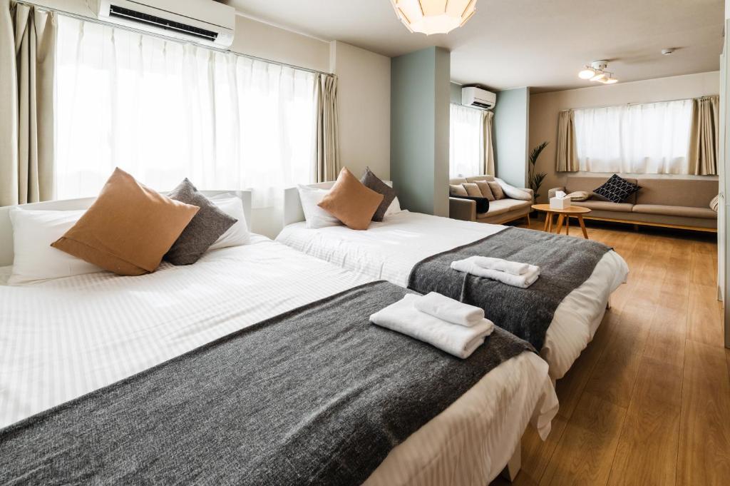a bedroom with two beds and a living room at Hale Hotel Miyakojima in Miyako-jima