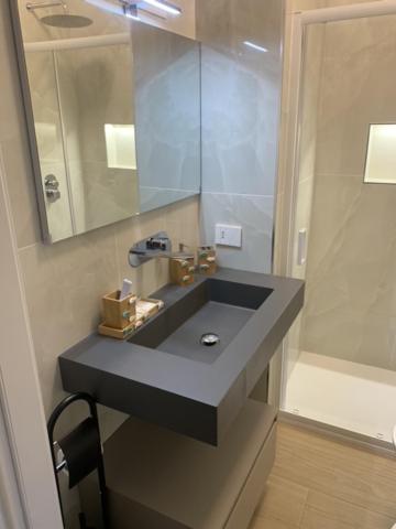 y baño con lavabo con espejo y ducha. en La Casa di Allegra, Monolocale a Le Grazie - Comune di Portovenere, en Portovenere