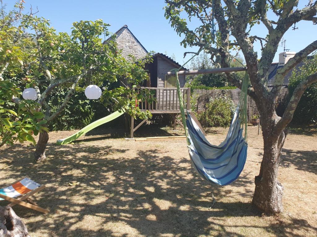 a blue hammock hanging from a tree in a yard at Maison typique bretonne a 5 min de la plage a pied in Crozon