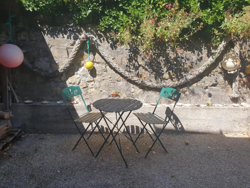 two chairs and a table in front of a wall at Maison typique bretonne a 5 min de la plage a pied in Crozon