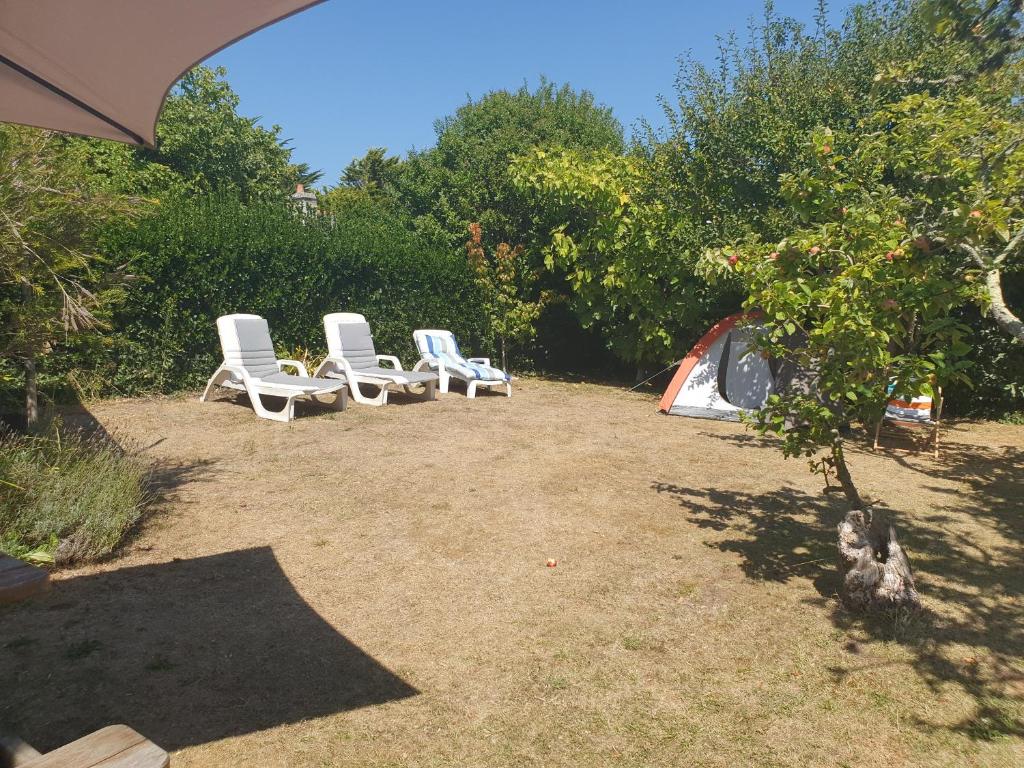a group of white chairs sitting in a yard at Maison typique bretonne a 5 min de la plage a pied in Crozon