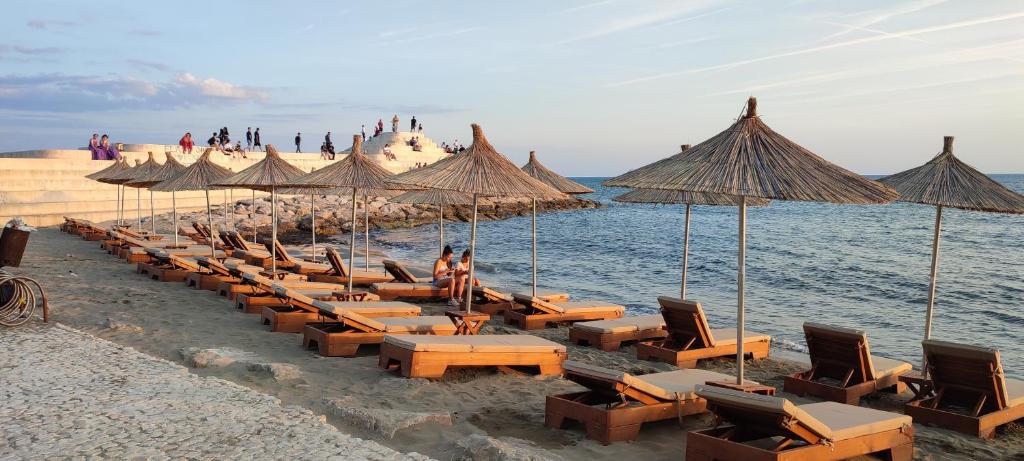 una fila de sillas y sombrillas en una playa en Promenade 3-Bedroom apartment with large balcony. en Durrës