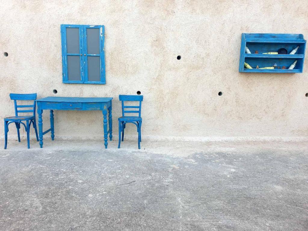 a blue table and two chairs next to a wall at Platsa Studios in Megás Limniónas